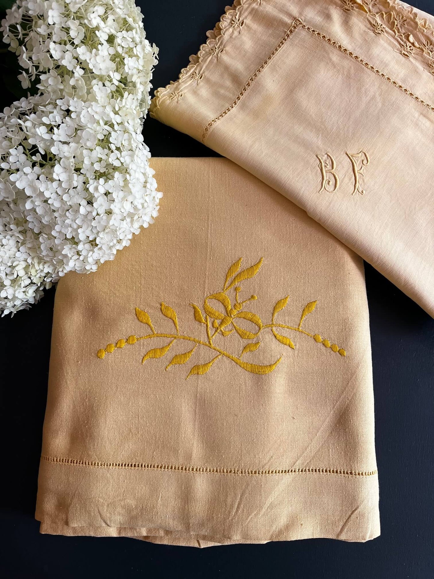 Mise en scène d’un lit avec drap ancien jaune et taies brodées