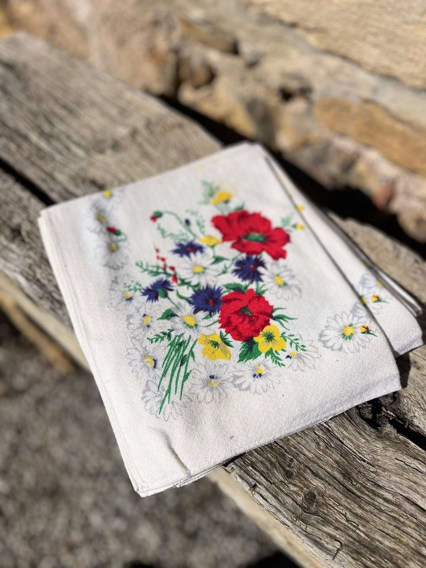 Lot de serviettes vintage fleuries dressées sur une table de jardin avec vaisselle ancienne
