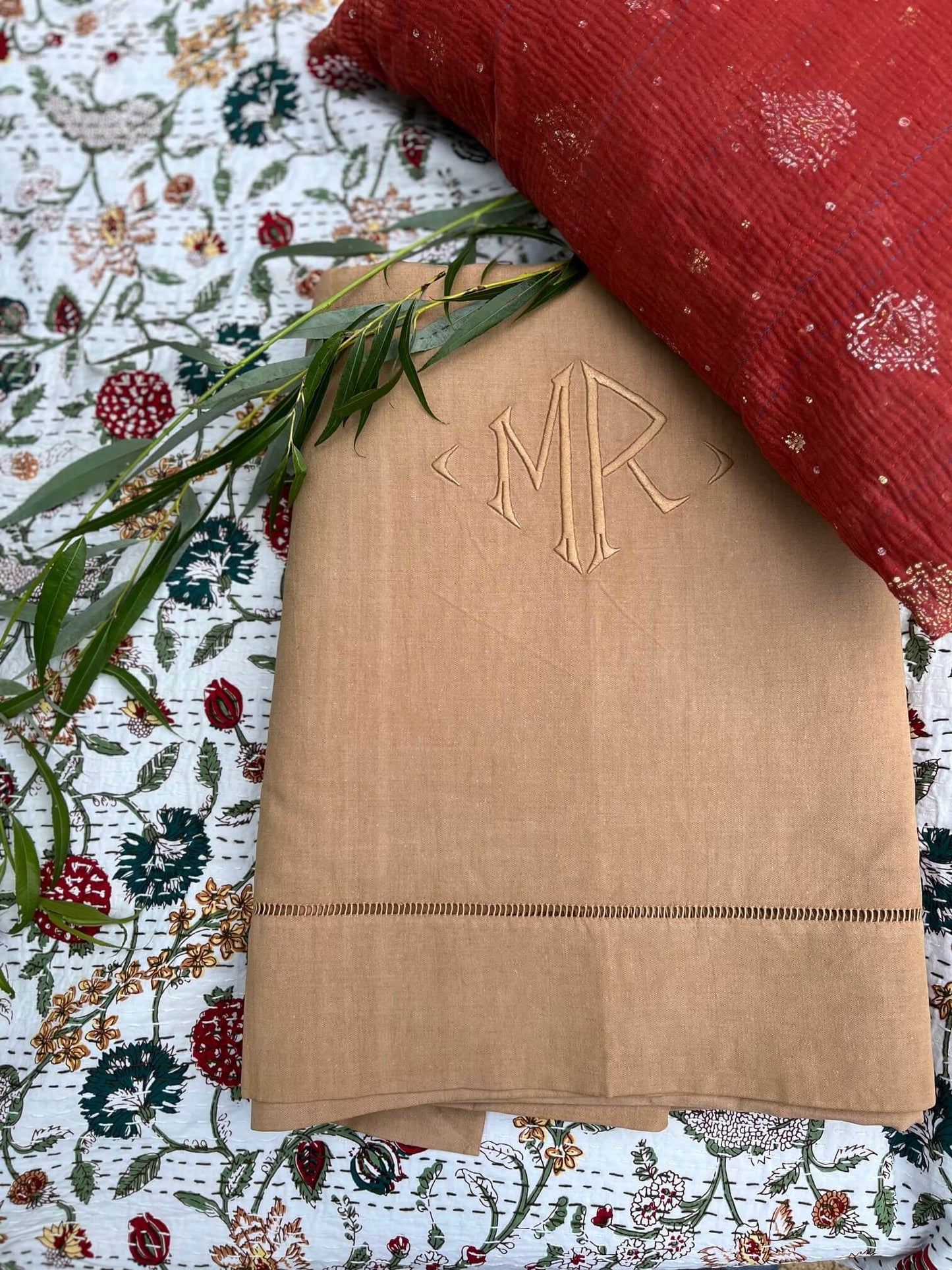 Drap ancien en coton beige brodé avec monogramme MR sur un lit floral