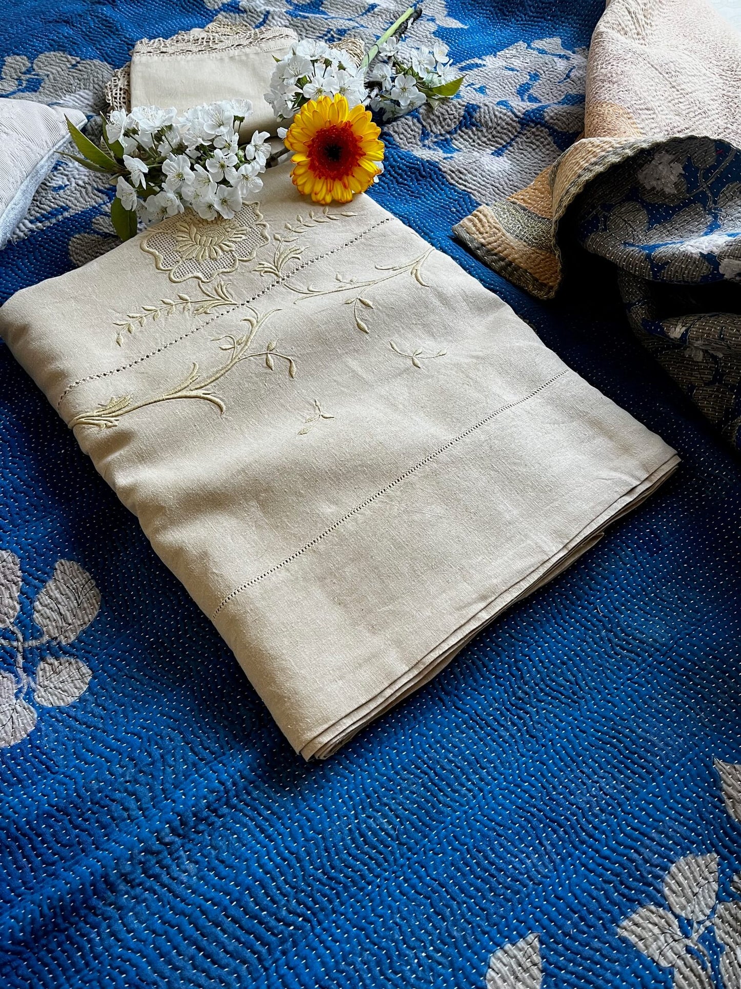 Kantha indien en coton associé à du linge ancien brodé et des fleurs pour une déco poétique