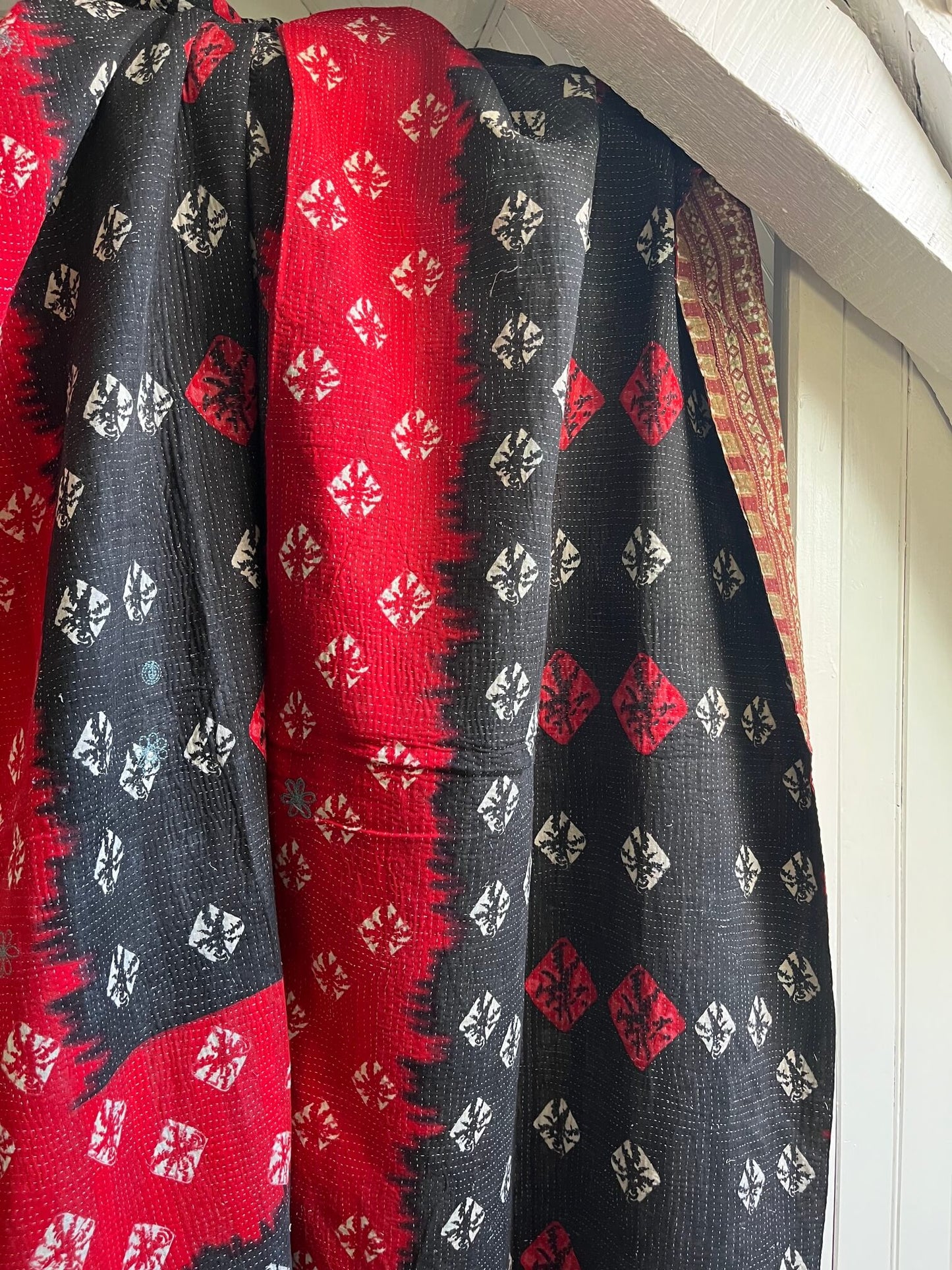 Kantha indien réversible rouge et noir utilisé en couvre-lit dans une décoration bohème chic, chaleureuse et authentique.