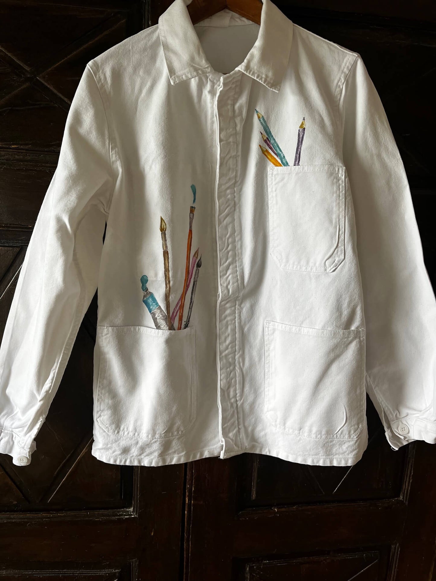 Veste d’artiste blanche customisée avec des crayons et pinceaux peints à la main sur les poches
