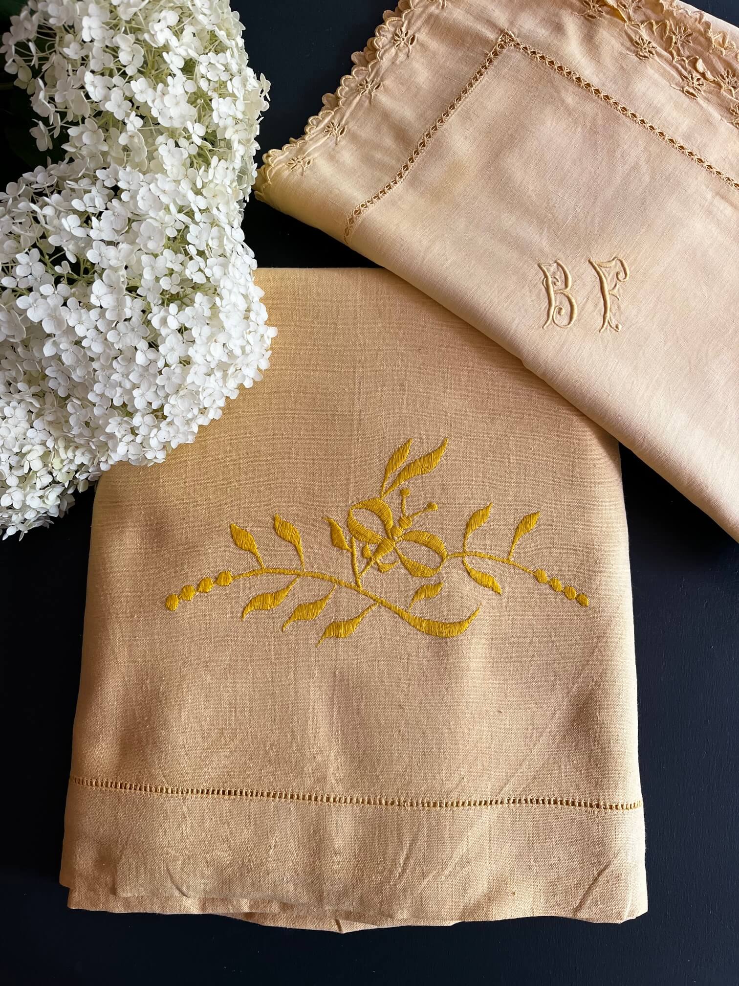 Mise en scène d’un lit avec drap ancien jaune et taies brodées