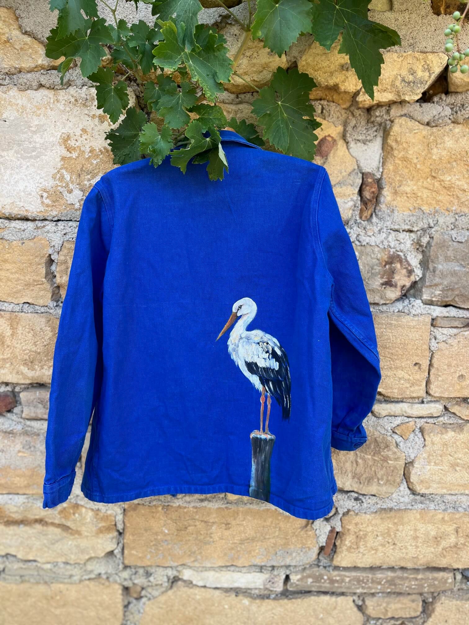 Dos d'un bleu de travail vintage français peint à la main représentant une cigogne – pièce unique Le Roi Arthur