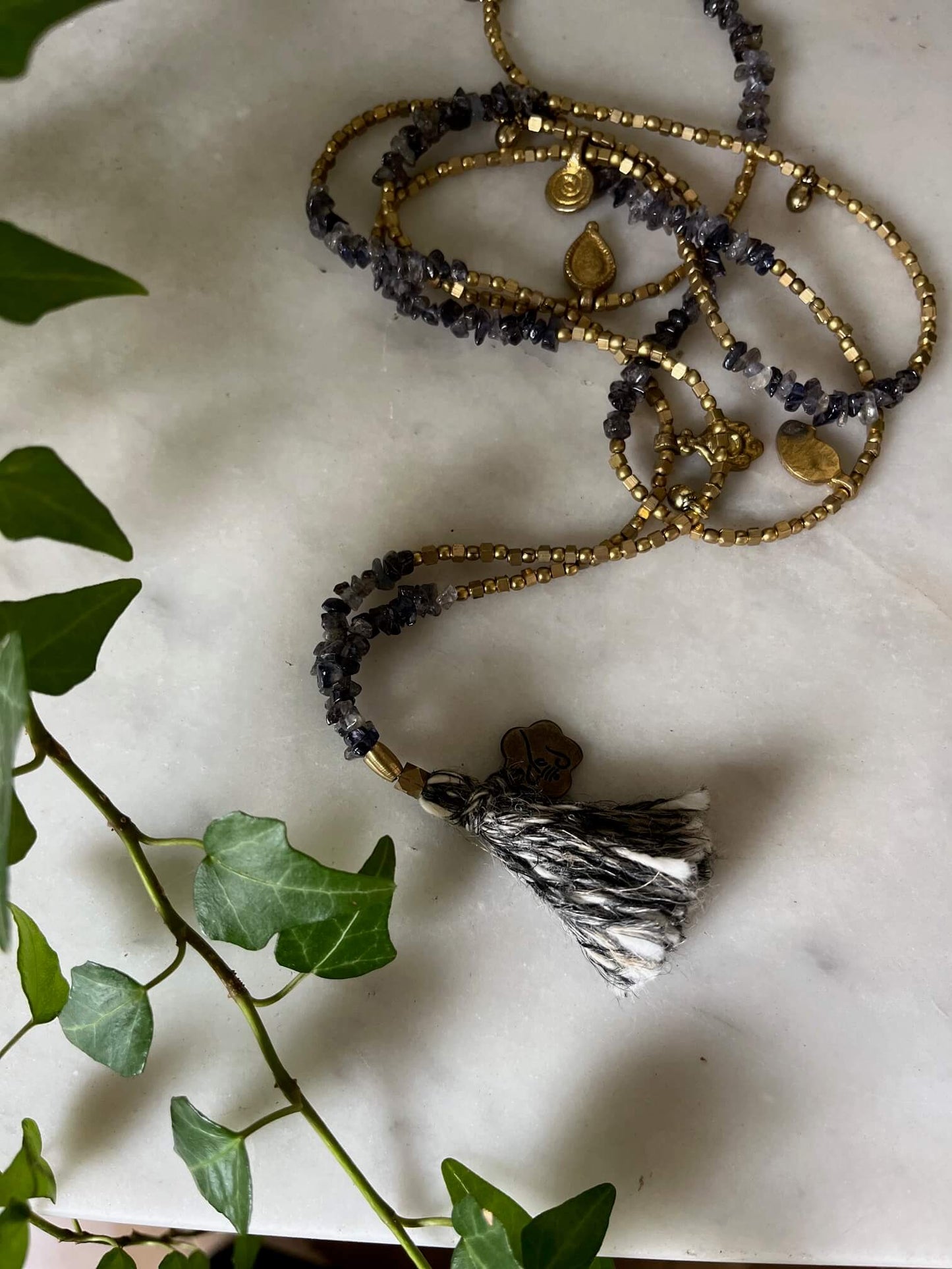 Détail des perles effet cailloux gris et or d’un collier sautoir artisanal.