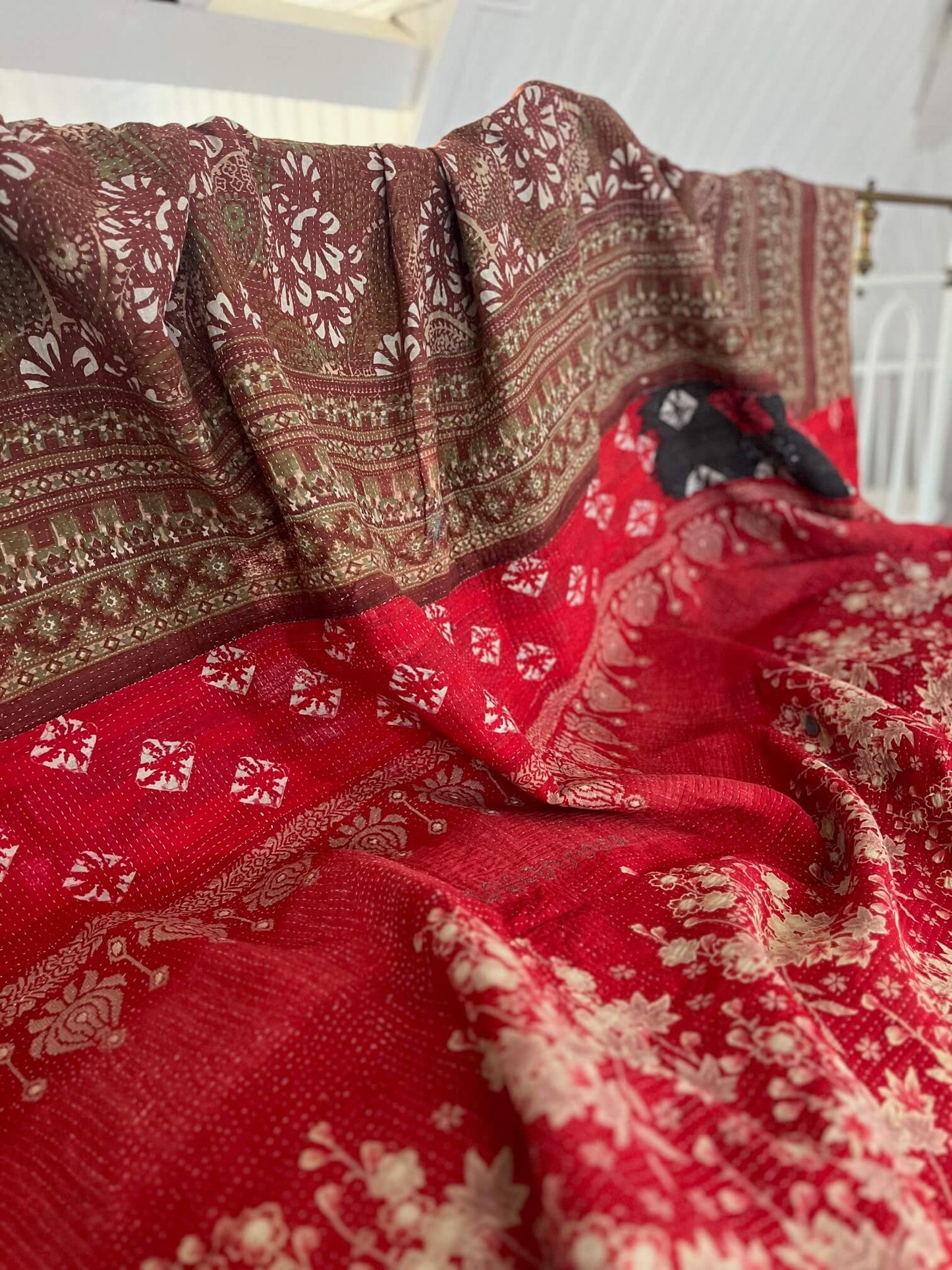 Détail de la broderie Kantha cousue à la main sur un couvre-lit indien en coton rouge et noir.