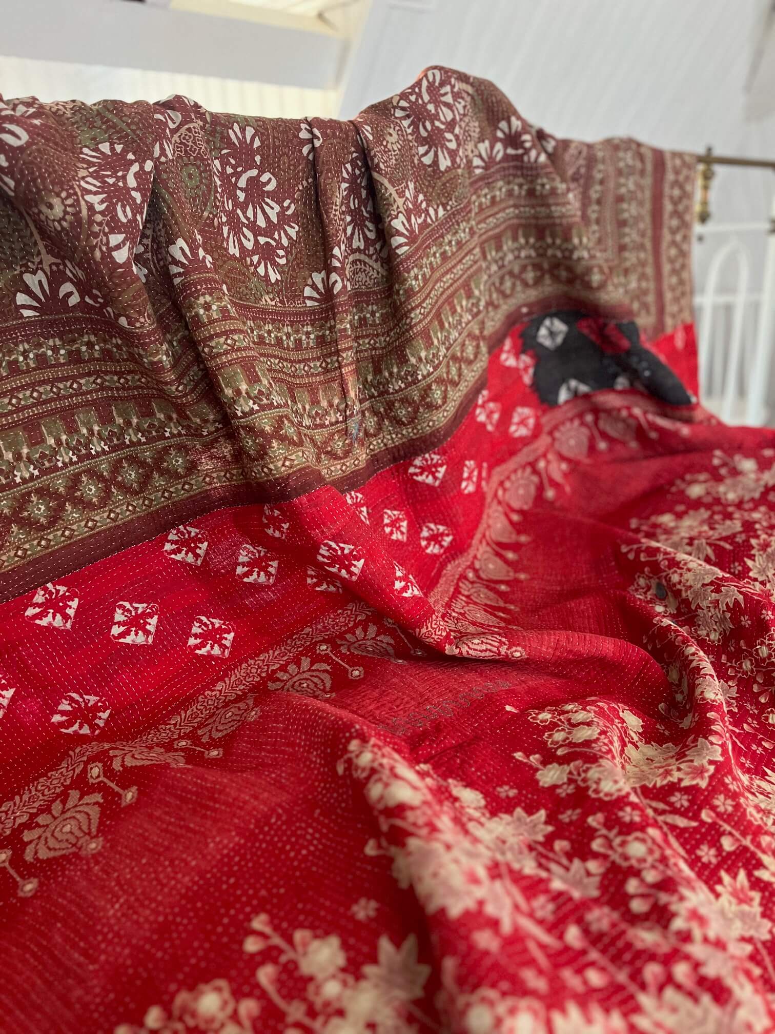 Détail de la broderie Kantha cousue à la main sur un couvre-lit indien en coton rouge et noir.