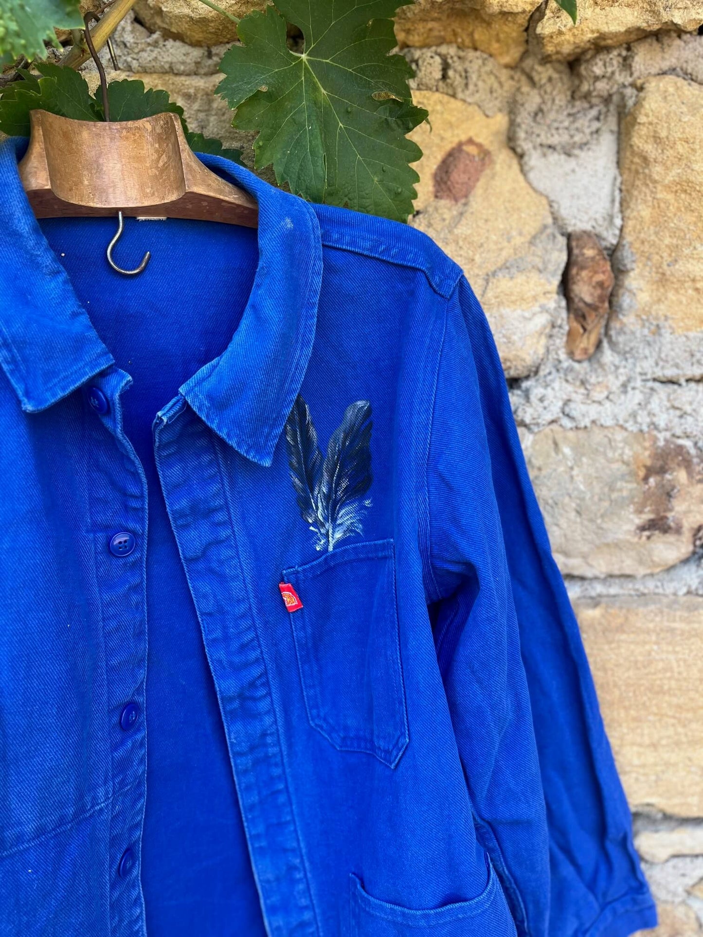 Détail de la cigogne peinte à la main sur un bleu de travail vintage français