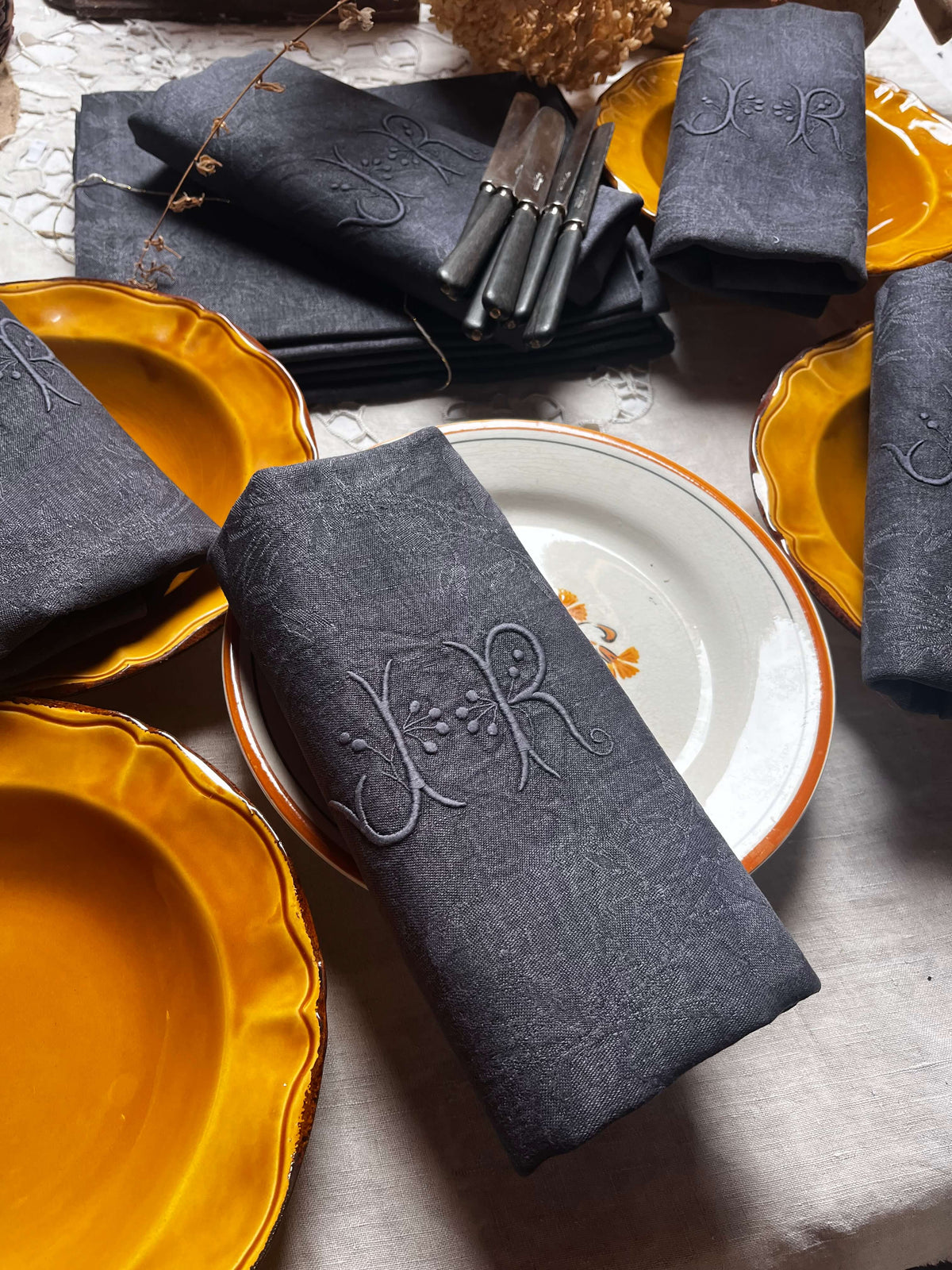 Détail du monogramme JR sur une serviette de table ancienne noir charbon
