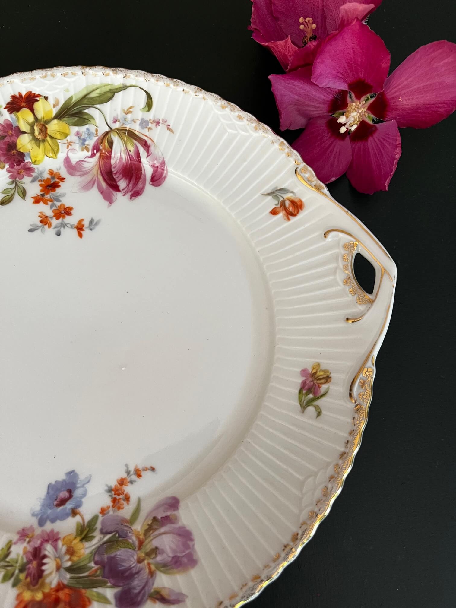 Gros plan motifs floraux délicats sur porcelaine du plat tarte vintage, finitions artisanales