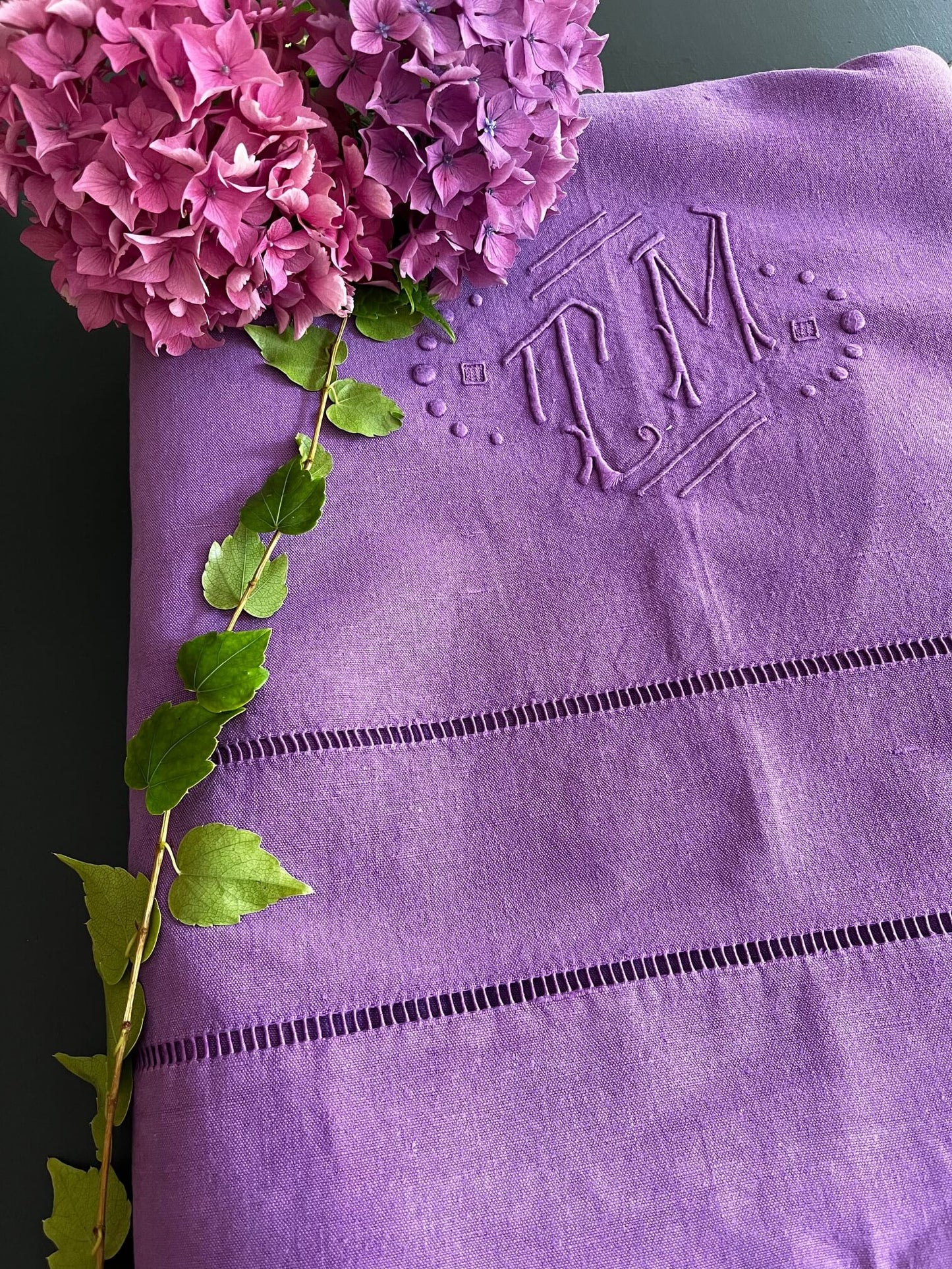 Drap ancien lilas utilisé comme nappe sur table en bois
