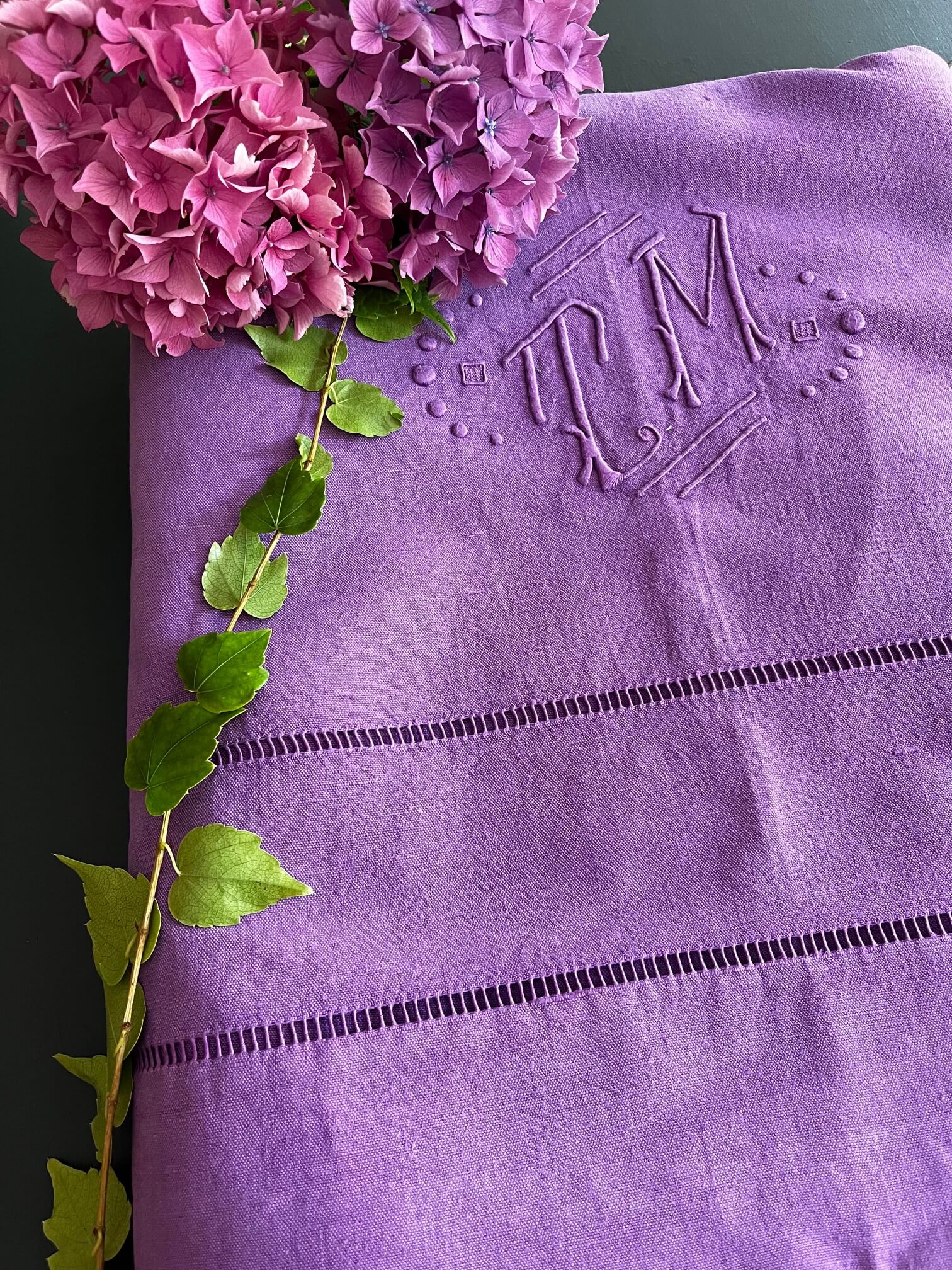 Drap ancien lilas utilisé comme nappe sur table en bois