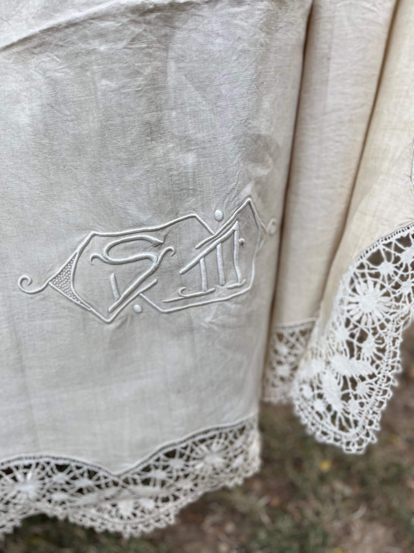 Détail de la broderie et dentelle sur un drap ancien en lin beige