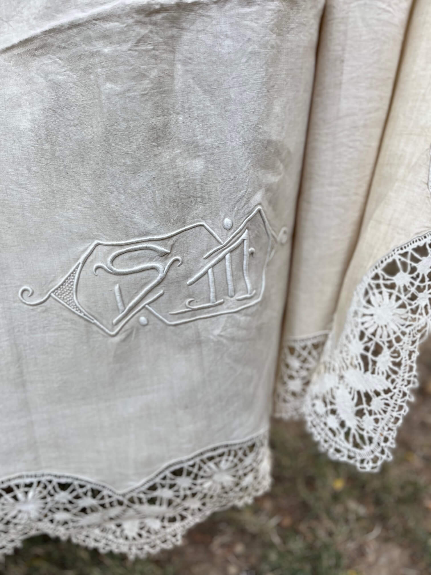 Détail de la broderie et dentelle sur un drap ancien en lin beige
