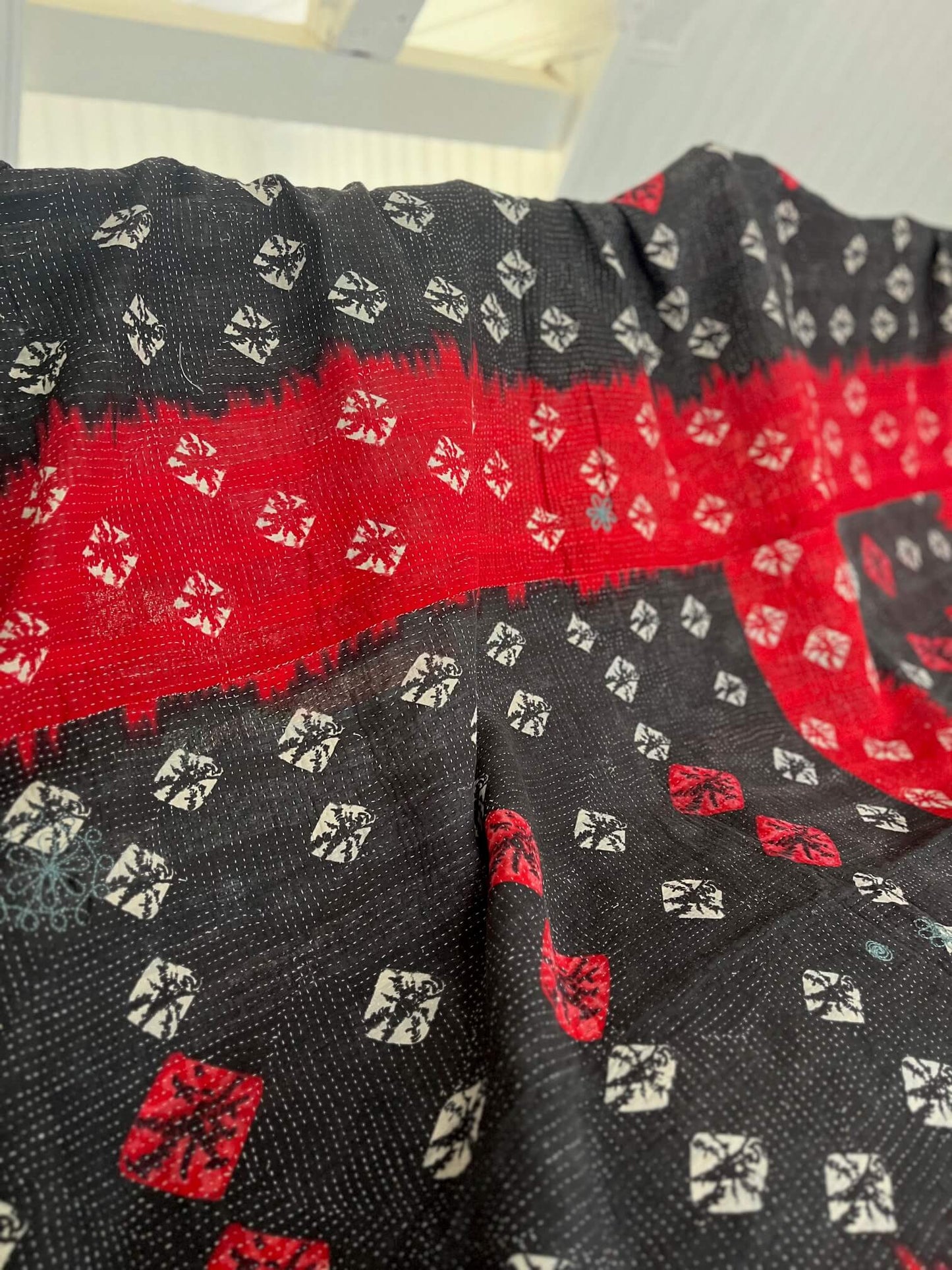 Verso d'un kantha indien réversible en coton rouge et noir, pièce artisanale unique réalisée à la main.
