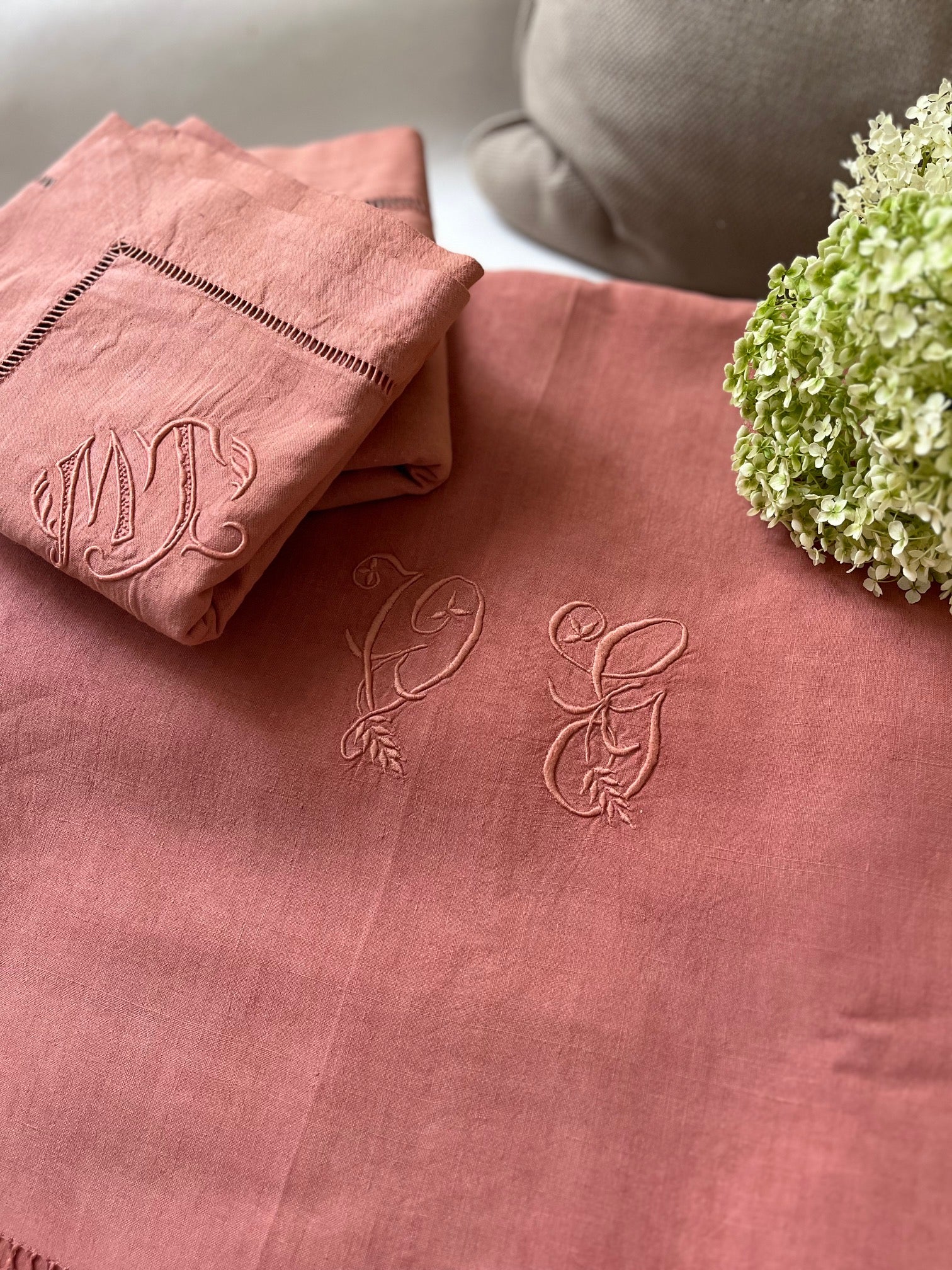 Drap ancien en lin terracotta et taies monogrammées dans une chambre élégante, authentique et chaleureuse.