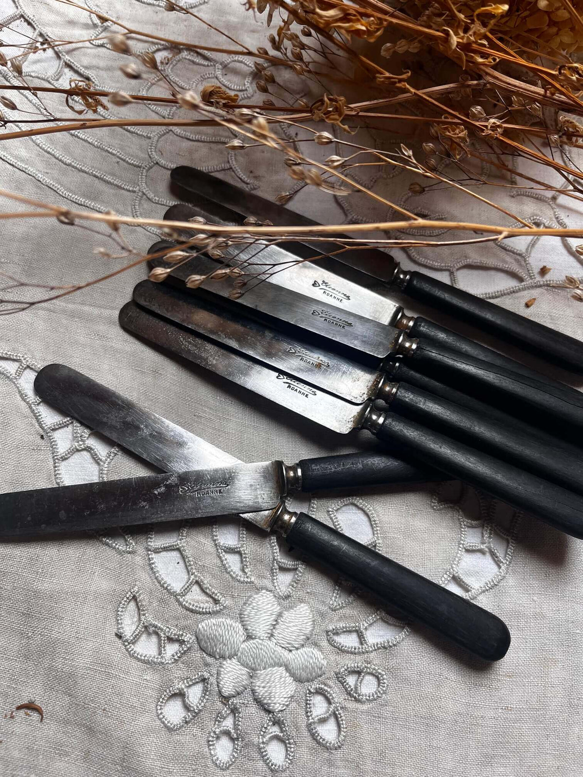 Lot de 11 couteaux de table anciens en métal argenté aux manches noirs
