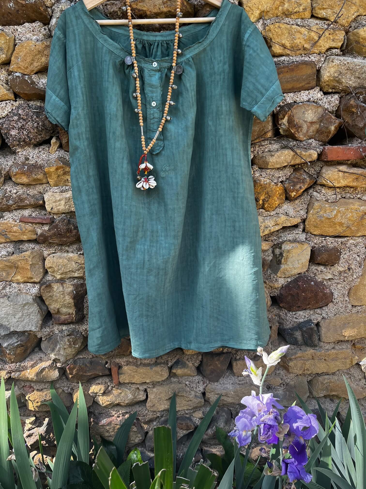 Robe verte en coton portée avec un sac rayé multicolore, look d’été frais et original