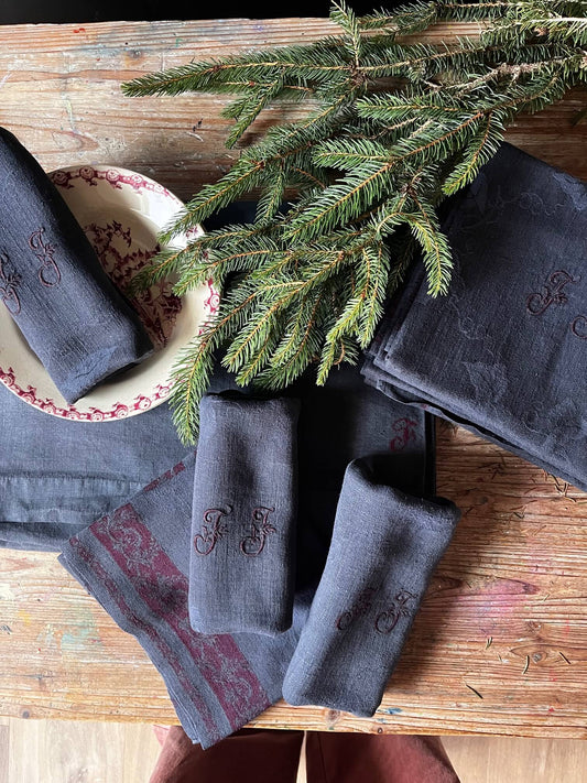 Serviette ancienne en coton damassé teinte charbon monogrammée JJ sur table décorée pour repas de fête