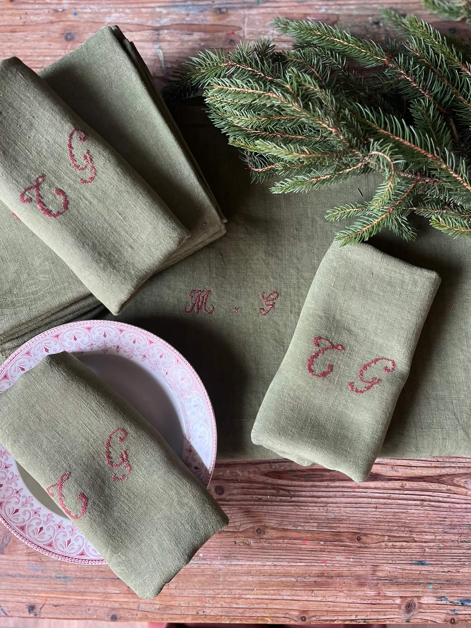 Serviette ancienne en coton damassé teinte kaki monogrammée CG sur table décorée pour repas de fête