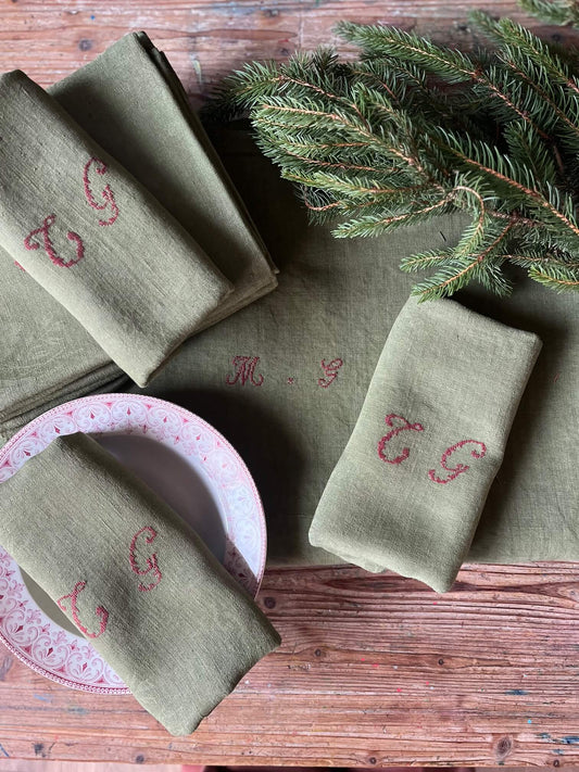 Serviette ancienne en coton damassé teinte kaki monogrammée CG sur table décorée pour repas de fête