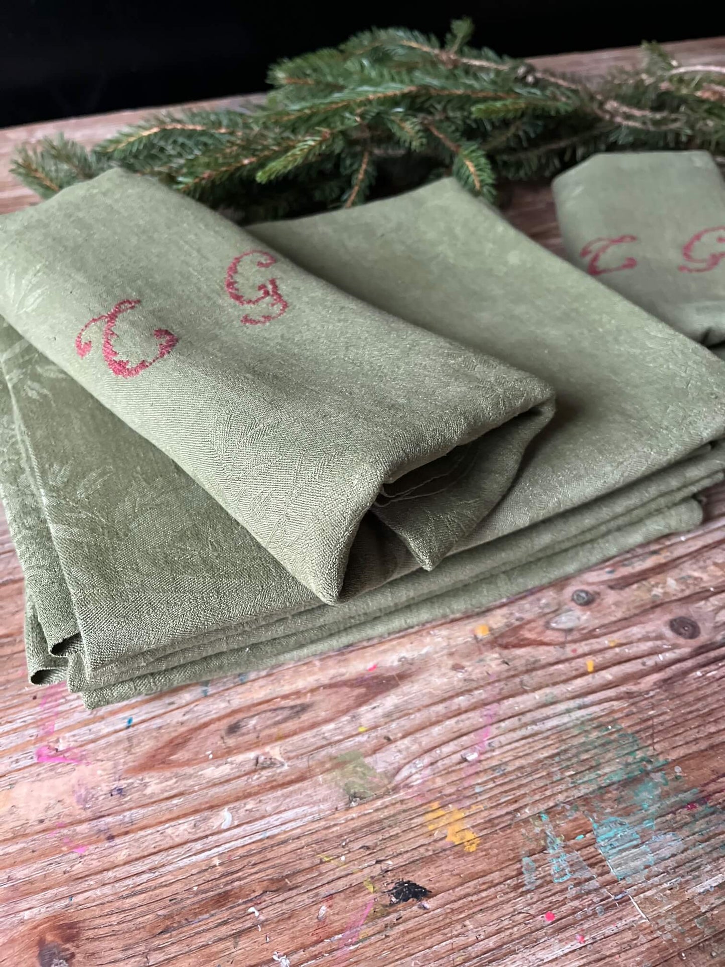 Gros plan sur le coton damassé kaki et le monogramme CG des serviettes anciennes avec finition artisanale