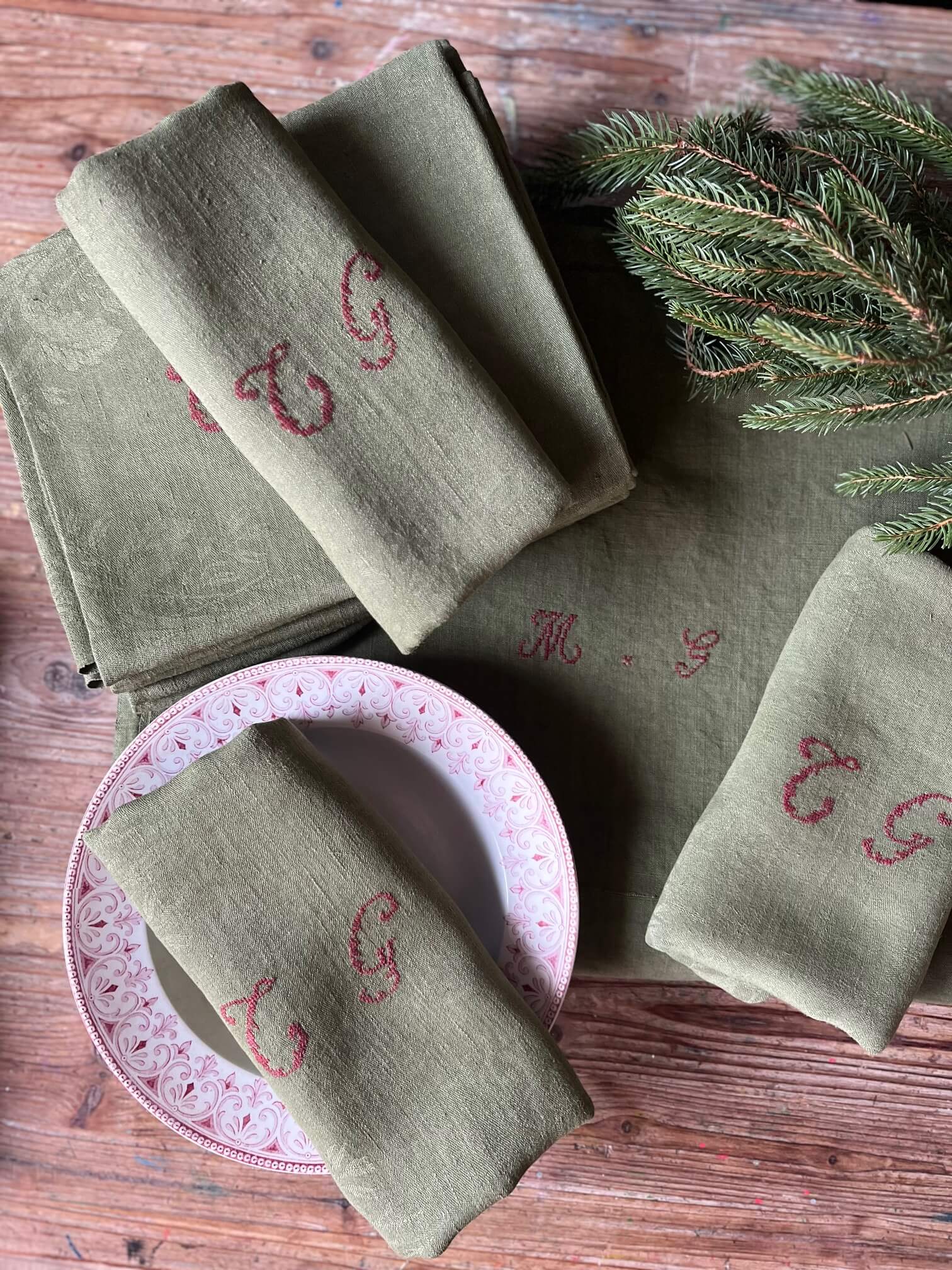  Lot de 9 serviettes anciennes en coton damassé teinte kaki monogrammées CG sur table décorée pour repas festif