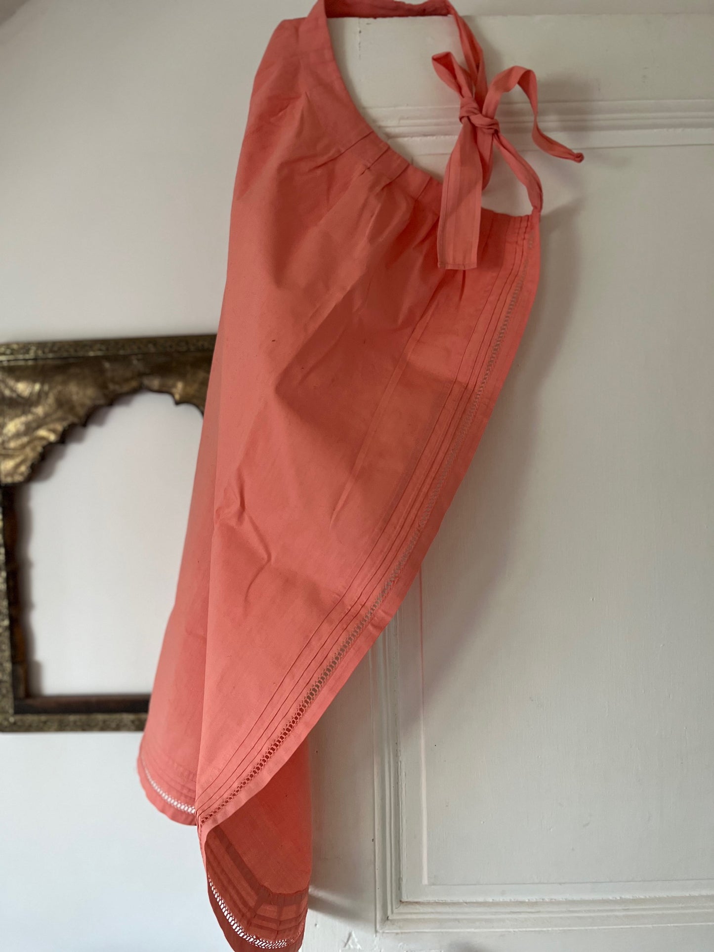 Tablier ancien teint artisanalement en coton rose saumon, élégant et unique, présenté en cuisine