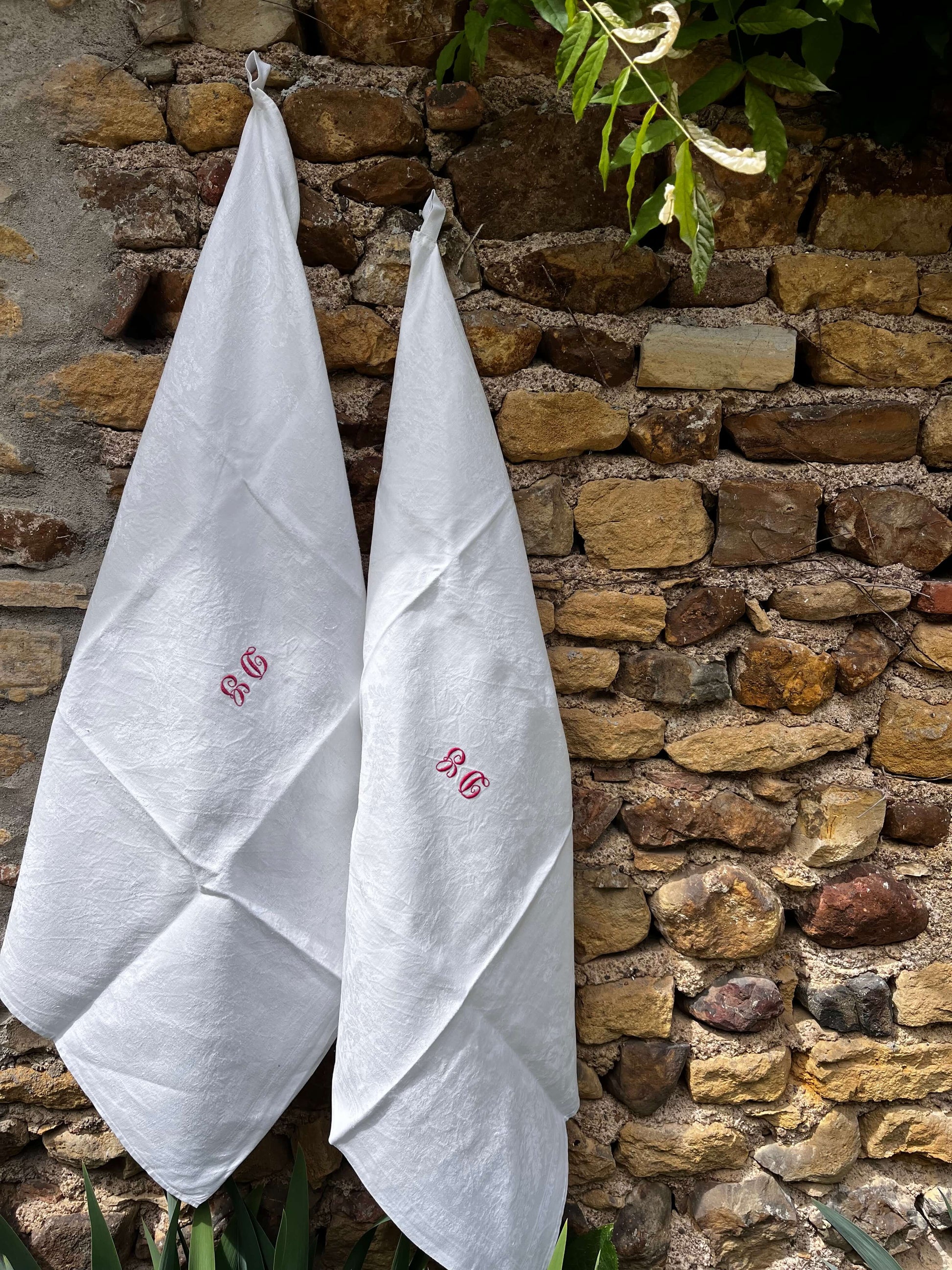 Torchon ancien monogrammé DG en coton damassé sur mur en pierre