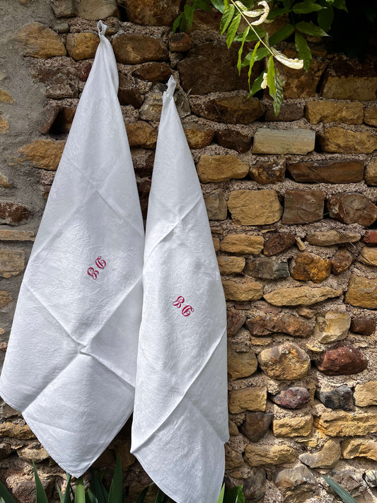 Torchon ancien monogrammé DG en coton damassé sur mur en pierre